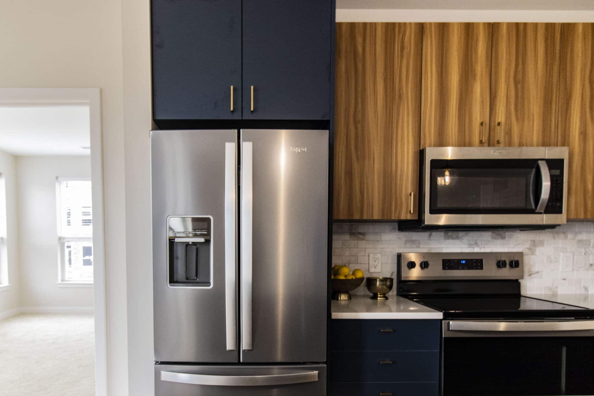 The James Apartments | Close-up of a modern kitchen stove and microwave with custom tile backsplash and decorative accents including a bowl of lemons and a brass bowl on the countertop | Luxury Apartments in Haverhill MA