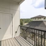 The James Apartments | Balcony with a wooden floor, black railing, and a view of a rooftop pavilion, with a closed door leading into the apartment | Luxury Apartments in Haverhill MA