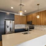 The James Apartments | Spacious kitchen with a stainless steel refrigerator, microwave, and oven, complemented by wooden cabinetry and a quartz countertop | Luxury Apartments in Haverhill MA