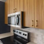 The James Apartments | Close-up of a modern kitchen stove and microwave with custom tile backsplash and decorative accents including a bowl of lemons and a brass bowl on the countertop | Luxury Apartments in Haverhill MA