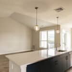 The James Apartments | Bright living space with vaulted ceiling, large windows, and an open-concept kitchen with a large island | Luxury Apartments in Haverhill MA